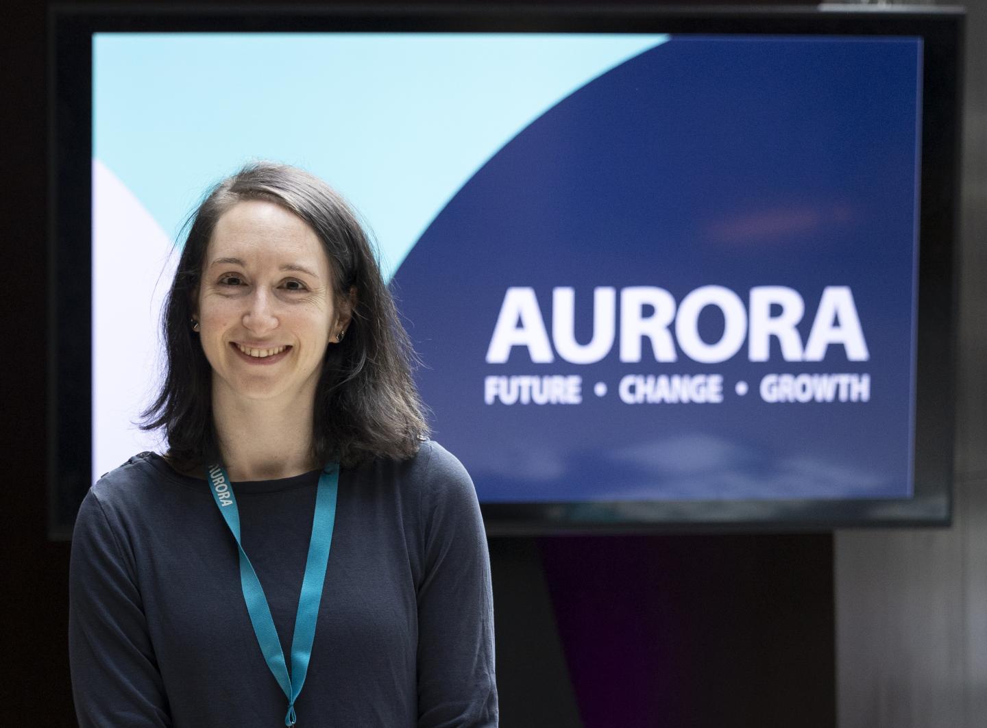 Woman smiling with Aurora programme signage in the background