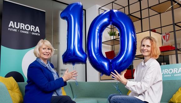 Two women holding shiny balloons making up number 10