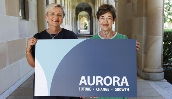 Two women holding a sign that says Aurora - future, change, growth