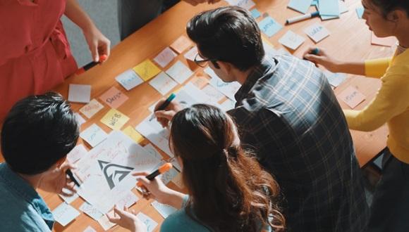 HE students working around a table in a group to brainstorm ideas