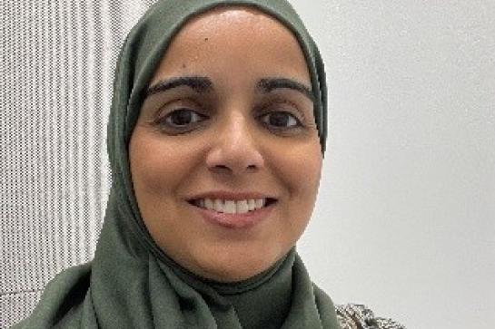 Salma Younis wearing a light-coloured headscarf and a patterned garment, seated indoors against a plain background.